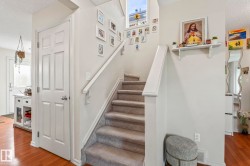 Staircase with carpeted treads and white painted handrails, complemented by a prominent window above - 