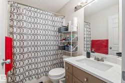 Bathroom featuring a vanity with an integrated sink, a large wall-mounted mirror, brushed nickel fixtures, and a toilet - 