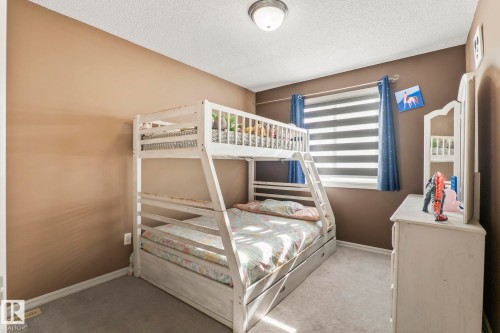 Carpeted room featuring a window with horizontal blinds, a ceiling-mounted light fixture, and neutral-toned walls - 220 85St, Edmonton, AB 