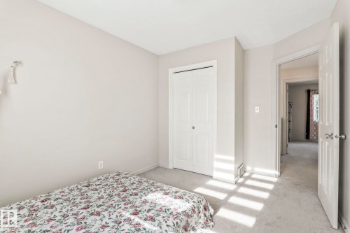 Bedroom featuring light gray wall paint, white trim, wall-to-wall carpeting, and a bi-fold closet door - 220 85St, Edmonton, AB 