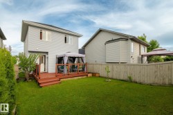 Expansive green lawn featuring a wooden deck with railing, direct access to the home, and a privacy fence - 