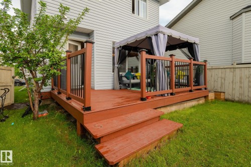 Wood-finish deck with integrated steps, featuring dark brown railing posts and black balusters - 220 85St, Edmonton, AB 