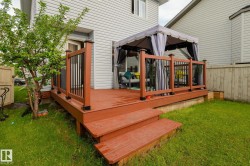Wood-finish deck with integrated steps, featuring dark brown railing posts and black balusters - 