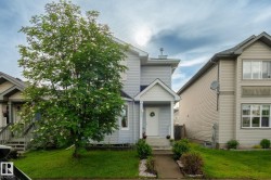 Two-story residence featuring light gray siding and a white front door with an overhanging porch - 