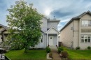 Two-story residence featuring light gray siding and a white front door with an overhanging porch - 220 85St, Edmonton, AB 