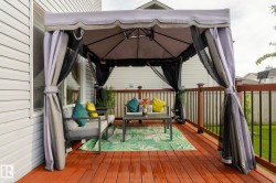 Spacious outdoor deck featuring a gazebo, wood deck flooring, and a railing with dark balusters - 