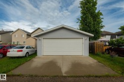 Detached garage with light grey siding and a white panel garage door - 