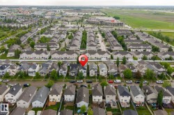 Aerial view of a residential neighborhood with detached homes and townhomes, featuring mature trees and paved streets - 