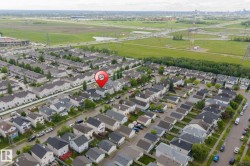 Aerial perspective of a residential neighborhood with a variety of housing styles, featuring a prominent green space - 