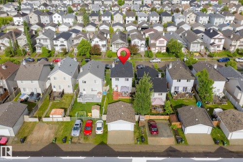 Aerial view of a residential property featuring a white two-story home with a dark shingle roof and a rear deck - 220 85St, Edmonton, AB 