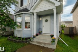 Residential facade featuring light blue horizontal siding, a covered front porch with white columns, and a bay window with a dark roofline - 