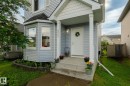 Residential facade featuring light blue horizontal siding, a covered front porch with white columns, and a bay window with a dark roofline - 220 85St, Edmonton, AB 