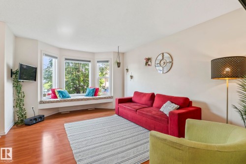 Living area featuring a bay window with a built-in window seat, wood-finish flooring, and light-toned wall finishes - 220 85St, Edmonton, AB 
