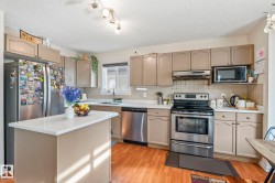 Kitchen featuring a central island with white countertop, stainless steel appliances, wood-finish flooring, ample cabinetry, and recessed lighting - 