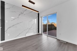 Feature wall with marble-look paneling, wood-finish flooring, and a modern linear pendant light fixture - 