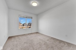 Bright interior space featuring a large window with horizontal blinds, neutral-toned carpet flooring, white walls, and a ceiling-mounted light fixture - 