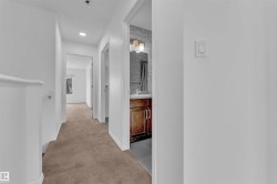 Hallway with plush brown carpeting, white walls, and recessed lighting - 