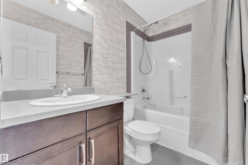 Bathroom featuring a dark wood-finish vanity with an undermount sink, a light-colored countertop, and a full-width mirror - 5405 Crabapple Loop, Edmonton, AB 