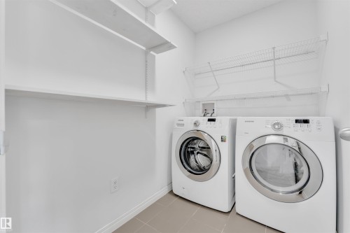 Laundry area featuring a side-by-side washer and dryer, tile flooring, and white wall shelving - 5405 Crabapple Loop, Edmonton, AB 