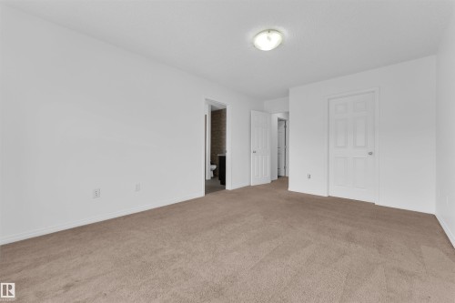 Carpeted room with white walls, white baseboards, and a flush mount ceiling light fixture - 5405 Crabapple Loop, Edmonton, AB 