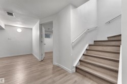 Interior staircase featuring wood-finish treads and risers, complemented by a white handrail and a metal wall-mounted railing - 