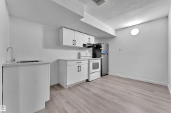 Compact kitchen area featuring white cabinetry, light-toned countertops, and wood-finish flooring - 