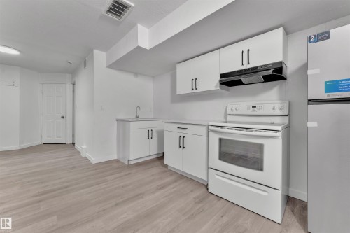 Kitchenette featuring white cabinetry, a stainless steel sink, and light wood-finish flooring - 5405 Crabapple Loop, Edmonton, AB 