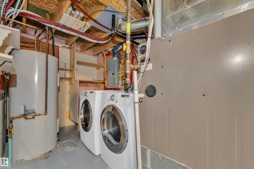 Dedicated utility area featuring a front-loading washer and dryer, water heater, and mechanical systems - 5405 Crabapple Loop, Edmonton, AB 