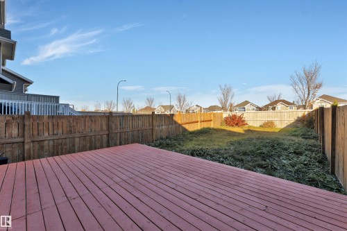 Expansive backyard featuring a large red-stained wood deck, perimeter wood fencing, and an established shrub border - 5405 Crabapple Loop, Edmonton, AB 