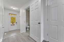 Entryway featuring a six-panel front door with upper glass paneling and transom window, light gray tile flooring, and wood-finish flooring - 