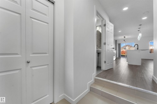 Entryway featuring a white paneled closet door, tile flooring, and a small step down to the main living area - 5405 Crabapple Loop, Edmonton, AB 