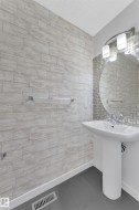 Pedestal sink with chrome fixtures, a circular mirror, and a contemporary vanity light - 