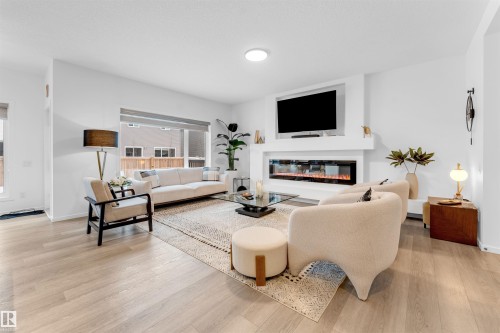 Living area featuring light wood-finish flooring, a contemporary linear fireplace, and a wall-mounted display recess - 6203 47 Avenue, Beaumont, AB 