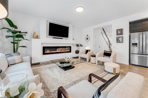 Contemporary living space featuring a built-in electric fireplace, integrated television niche, and light wood-finish flooring - 6203 47 Avenue, Beaumont, AB 