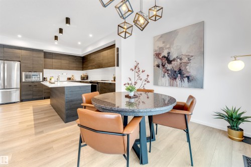 Modern kitchen featuring wood-finish cabinetry, stainless steel appliances, a center island with white countertop, and light wood-finish flooring - 6203 47 Avenue, Beaumont, AB 
