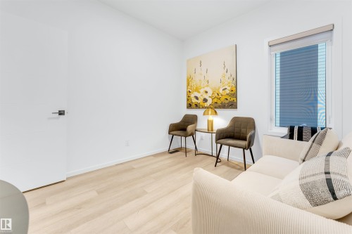 Bright interior space featuring a window with integrated blinds, light wood-finish flooring, and white baseboards - 6203 47 Avenue, Beaumont, AB 