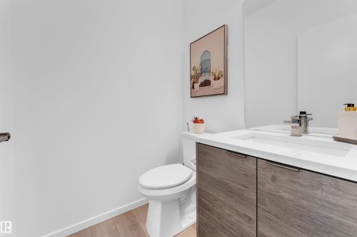 Modern bathroom vanity with wood-finish cabinetry, integrated sink, and polished chrome faucet - 6203 47 Avenue, Beaumont, AB 