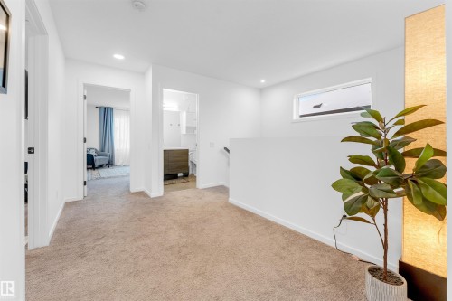 Upper level hallway featuring plush carpeting, crisp white walls, recessed lighting, and a horizontal window - 6203 47 Avenue, Beaumont, AB 