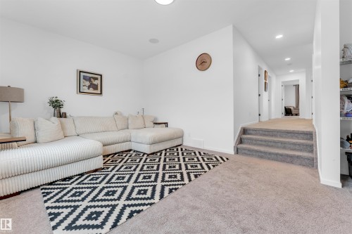 Spacious recreational area featuring recessed lighting, light-toned carpeting, and a three-step carpeted staircase leading to an interior hallway - 6203 47 Avenue, Beaumont, AB 