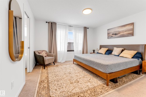 Carpeted bedroom with a window featuring sheer and opaque drapes - 6203 47 Avenue, Beaumont, AB 