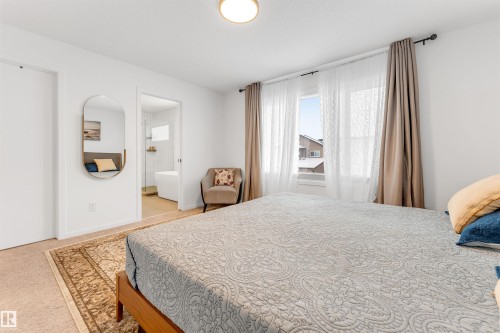 Bright bedroom with neutral tone carpet flooring and a wide window - 6203 47 Avenue, Beaumont, AB 