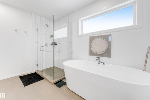 Freestanding soaking tub complemented by a glass-enclosed shower with vertical subway tile - 6203 47 Avenue, Beaumont, AB 