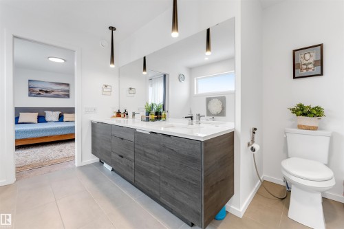 Spacious bathroom featuring a double vanity with wood-finish cabinetry, white countertop, and dual sinks - 6203 47 Avenue, Beaumont, AB 