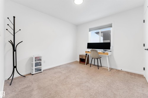 Carpeted room featuring a single window with blinds, white walls, and a ceiling-mounted light fixture - 6203 47 Avenue, Beaumont, AB 