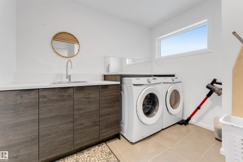 Laundry area featuring a wood-finish vanity with an integrated sink, a white countertop, and contemporary cabinetry - 6203 47 Avenue, Beaumont, AB 