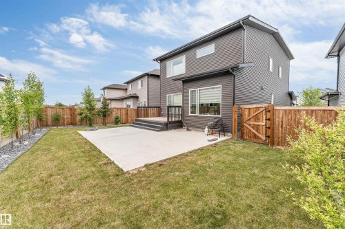 Spacious backyard featuring a concrete patio, wooden privacy fencing, and a multi-level deck with dark railing - 6203 47 Avenue, Beaumont, AB 