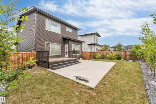 Expansive backyard featuring a large concrete patio and a raised wood-finish deck - 6203 47 Avenue, Beaumont, AB 