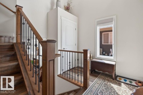 Staircase featuring wood-finish treads and risers, a wood newel post, and wrought iron balusters - 71 Ratelle Circle, St. Albert, AB 
