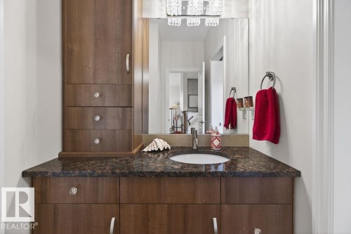 Wood-finish vanity with a dark speckled countertop and an integrated sink - 71 Ratelle Circle, St. Albert, AB 