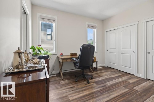 Room featuring wood-finish flooring, two windows with blinds, and white sliding closet doors - 71 Ratelle Circle, St. Albert, AB 